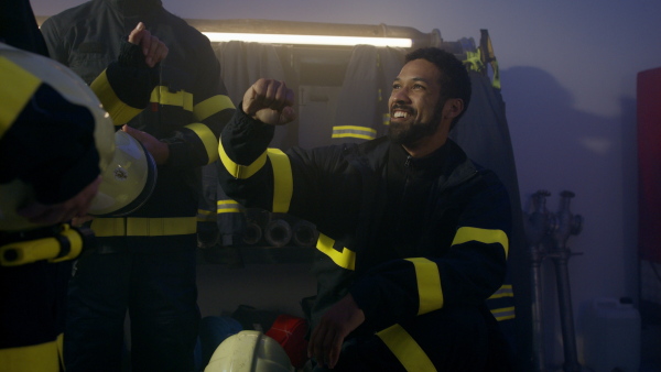 Happy firefighters men and woman after an action celebrating success indoors in fire station