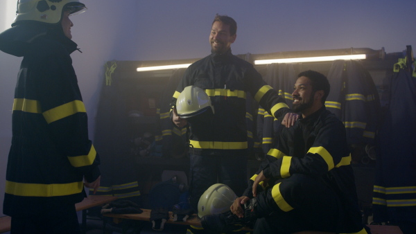 Happy firefighters men and woman after an action celebrating success indoors in fire station