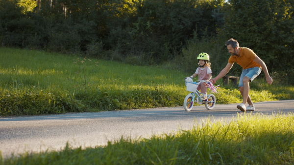 Mature father teaching his daughter how to ride a bike.