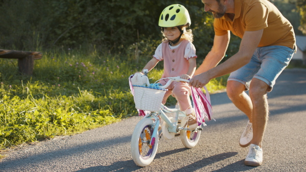 Mature father teaching his daughter how to ride a bike.