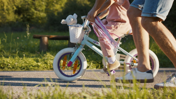 A side view of mature father teaching his daughter how to ride a bike.