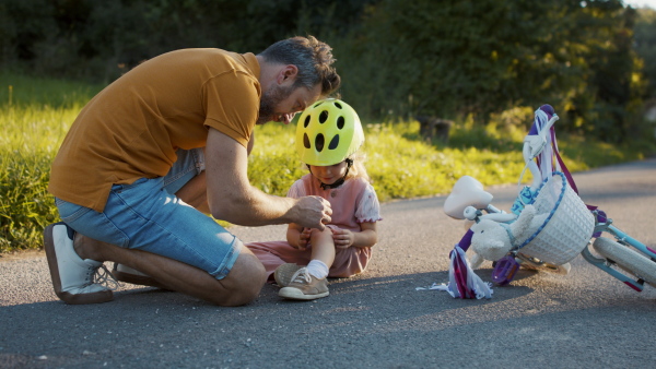 A father taking care of his daughter after she fell from bicycle.