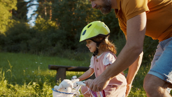 Mature father teaching his daughter how to ride a bike.