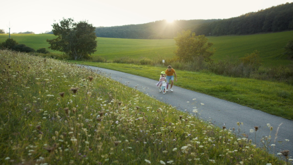 Mature father teaching his daughter how to ride a bike.