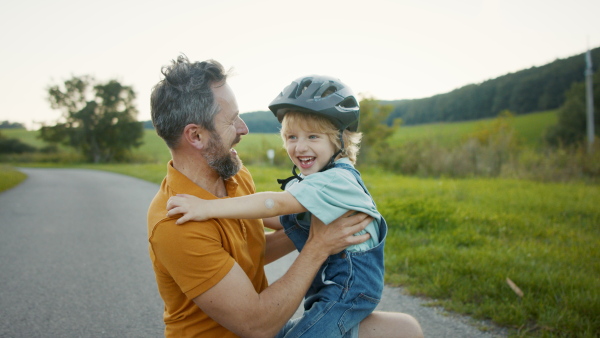 Mature father holding and hugging his son after bike riding training, looking at camera.