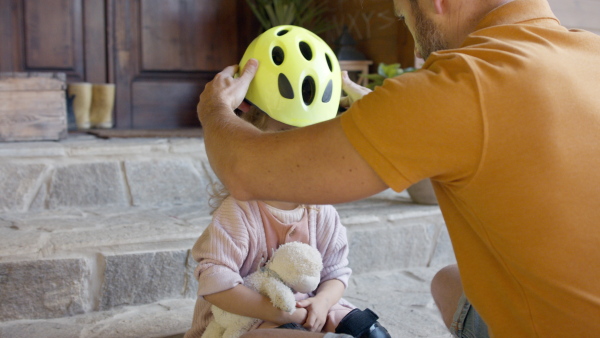 Mature father preparing his daughter for bike riding training.