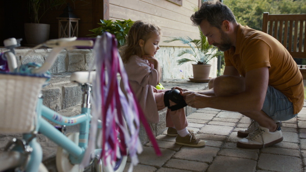 Mature father preparing his daughter for bike riding training.