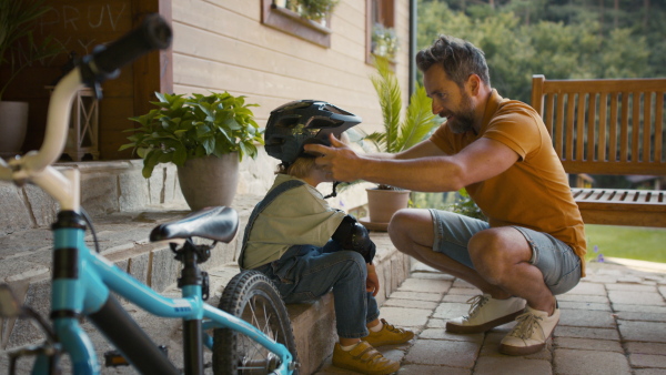 Mature father preparing his son for bike riding training.