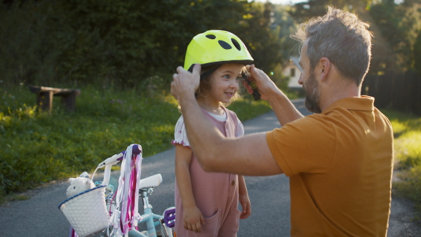 Mature father preparing his daughter for bike riding training.