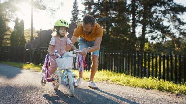 Mature father teaching his daughter how to ride a bike.