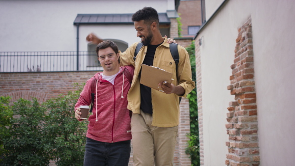 A young man with Down syndrome and his mentoring friend walking and embracing outdoors