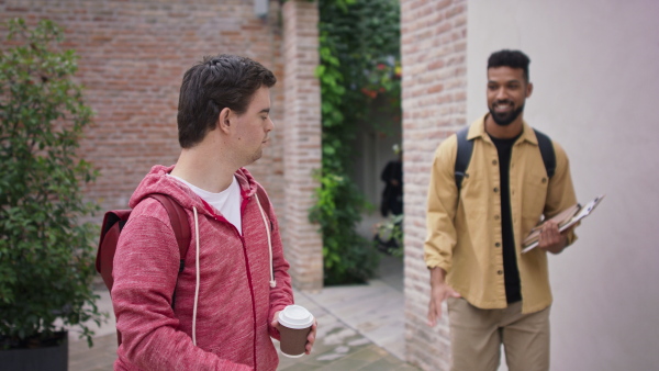 A young man with Down syndrome and his mentoring friend meeting and greeting outdoors