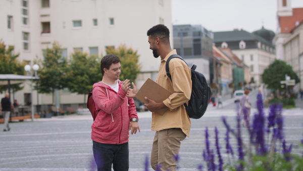 A young man with Down syndrome and his mentoring friend meeting and greeting outdoors in town