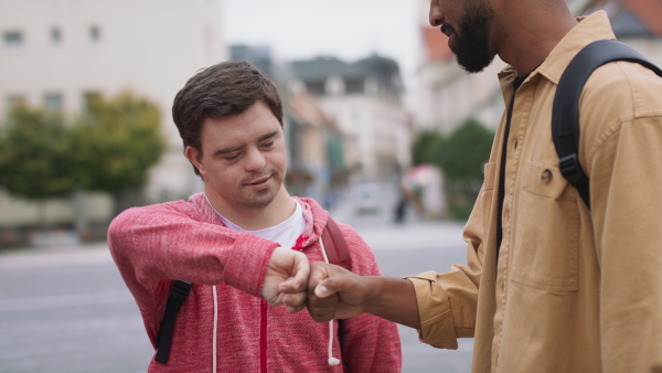 A close up of young man with Down syndrome and his mentoring friend meeting and greeting outdoors in town