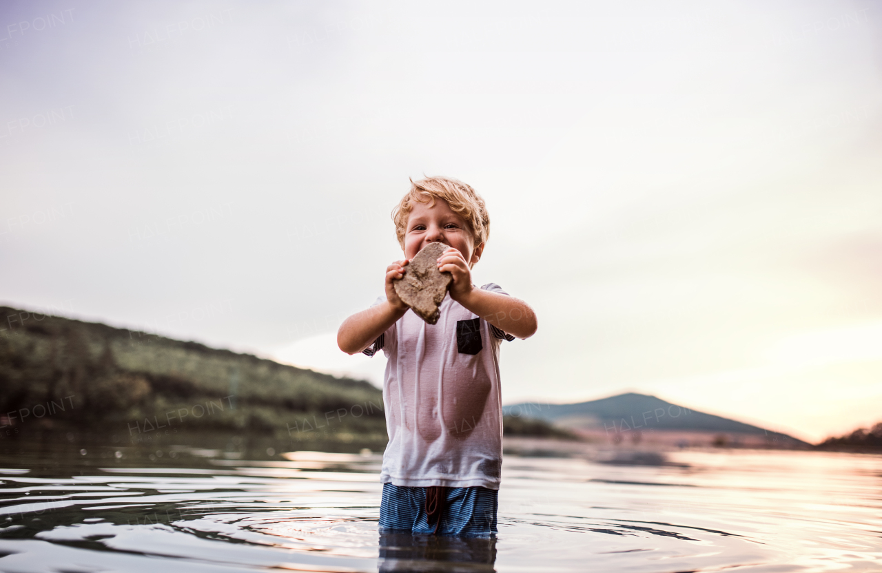 A small toddler boy playing outdoors by the river in summer. Copy space.