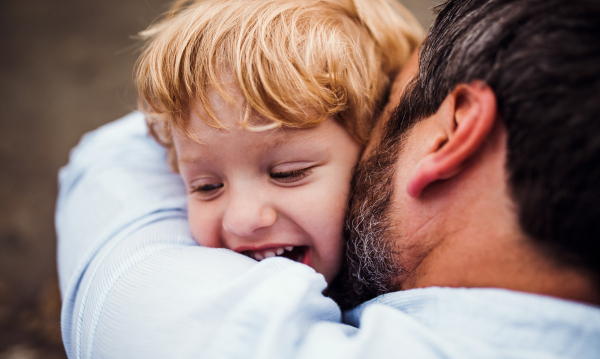 A close-up of mature father with a toddler boy outdoors by the river in summer.