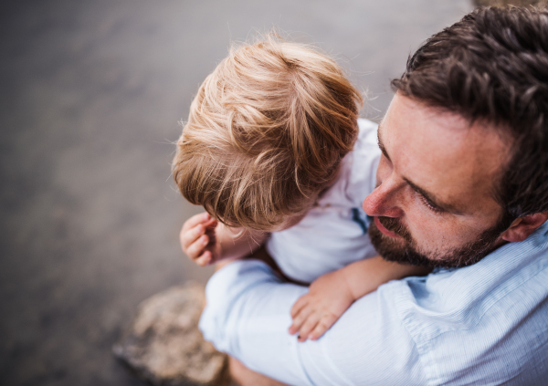 A top view of mature father with a toddler boy outdoors by the river in summer.