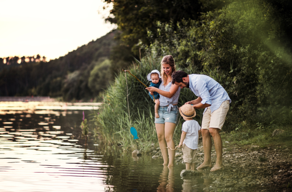 A young family with two toddler children spending time outdoors by the river in summer.