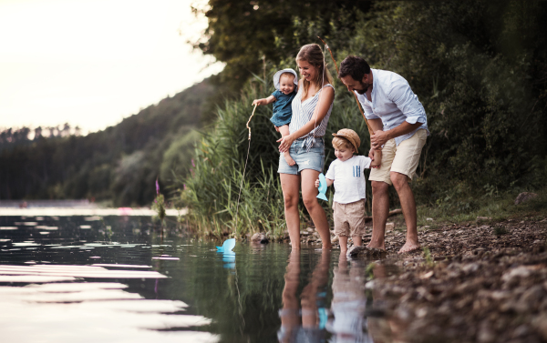 A young family with two toddler children spending time outdoors by the river in summer.