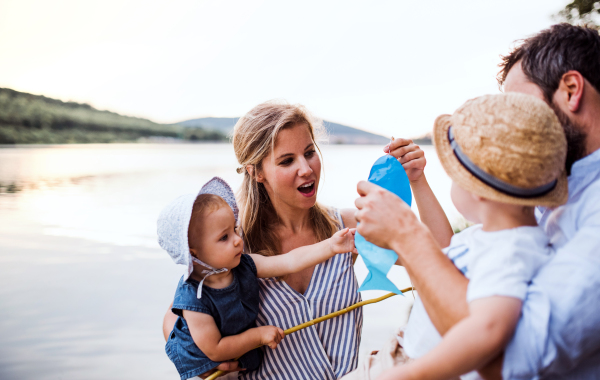 A young family with two toddler children spending time outdoors by the river in summer.