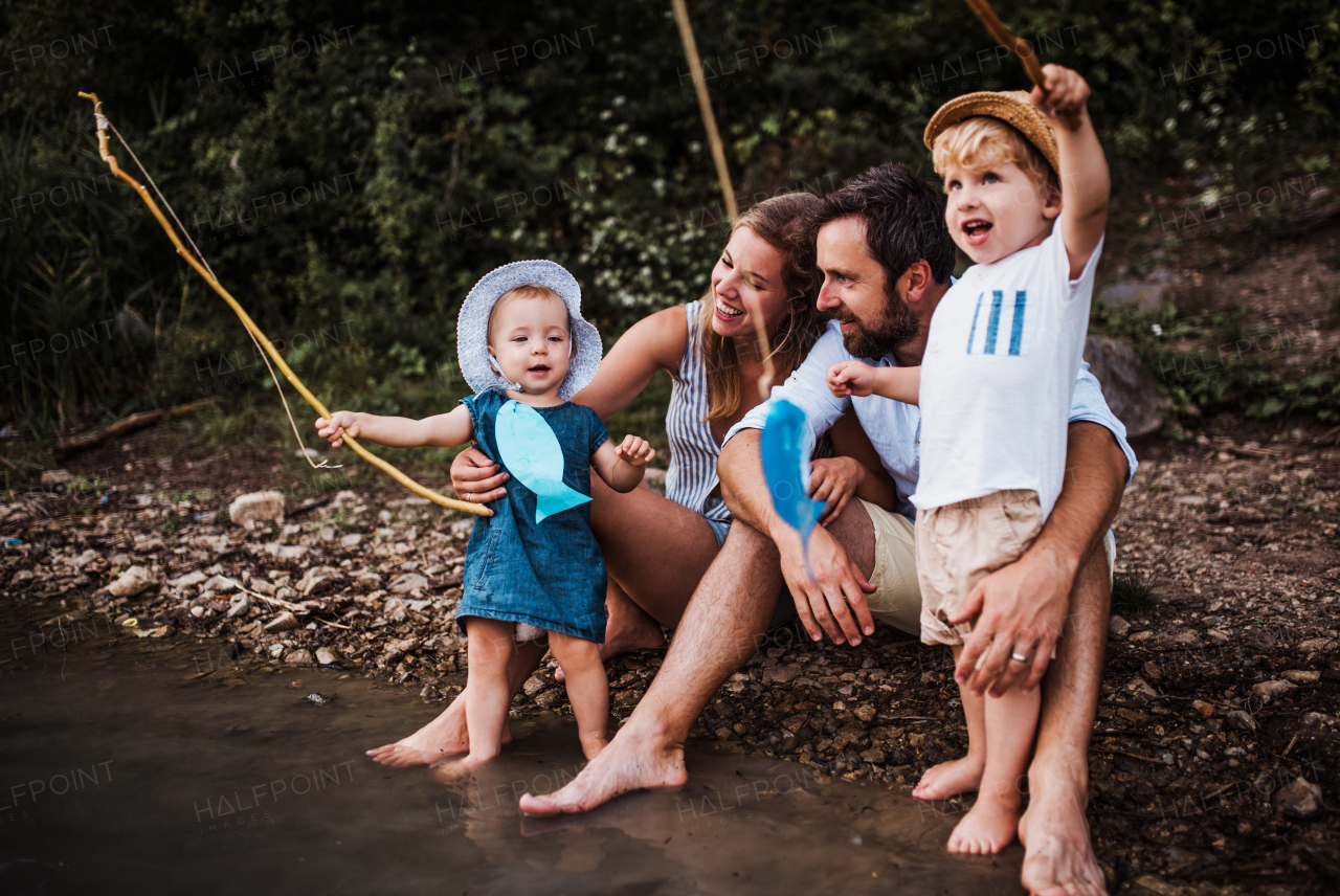 A young family with two toddler children spending time outdoors by the river in summer.