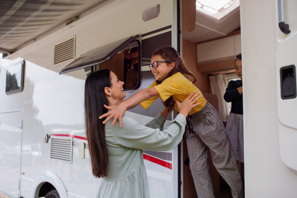 A mother with daughters standing by car outdoors in campsite at dusk, caravan family holiday trip.