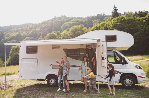 A multi-generation family getting out of car outdoors in nature, caravan holiday trip.