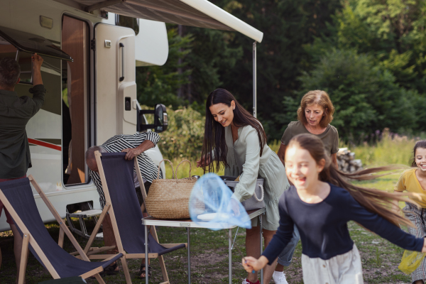 Happy multi-generation family unpacking and talking by car, caravan holiday trip.