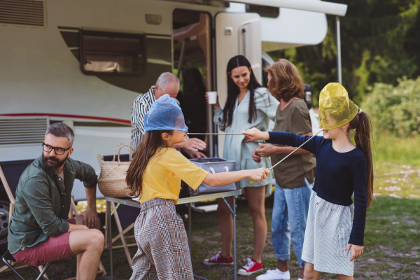 Happy multi-generation family unpacking and talking by car, caravan holiday trip.