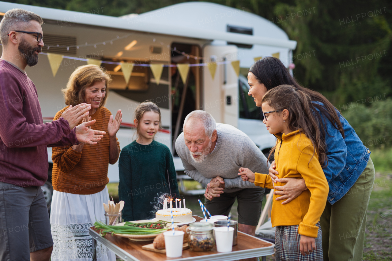 A multi-generation family celebrating birthday outdoors at campsite, caravan holiday trip.