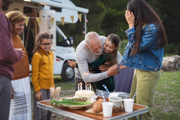 A small girl celebrating birthday outdoors at campsite, multi-generation family caravan holiday trip.