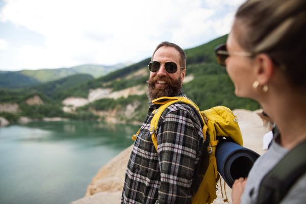 A happy mature couple on hiking trip on summer holiday, walking by lake.