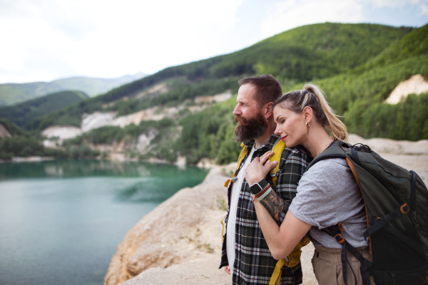 A happy mature couple on hiking trip on summer holiday, resting by lake.