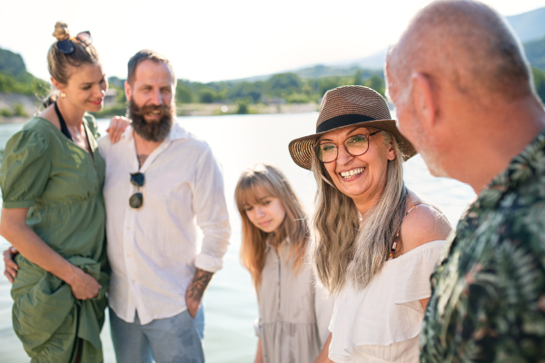 Portrait of happy multigeneration family on summer holiday, walking by lake.