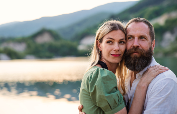 Portrait of happy mature couple in love hugging in nature, looking at camera.