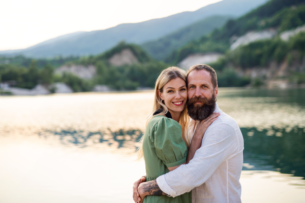 Portrait of happy mature couple in love hugging in nature, looking at camera.