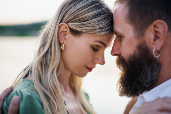 A close-up portrait of happy mature couple in love hugging in nature.