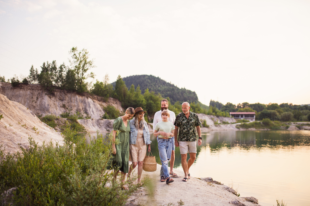 Portrait of happy multigeneration family on summer holiday, walking by lake.