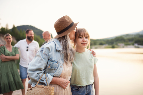 Portrait of happy multigeneration family on summer holiday, walking by lake.