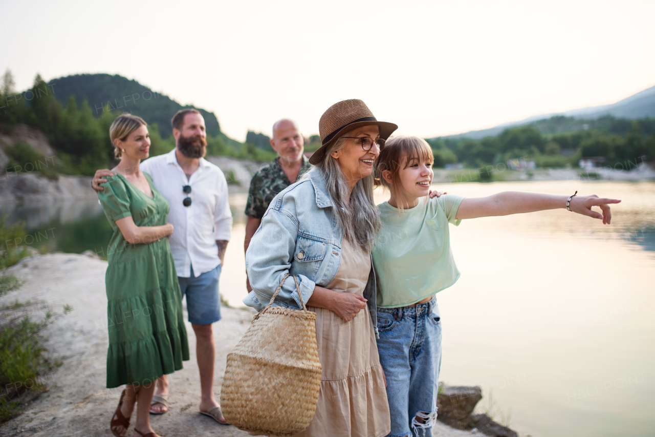 Portrait of happy multigeneration family on summer holiday, walking by lake.