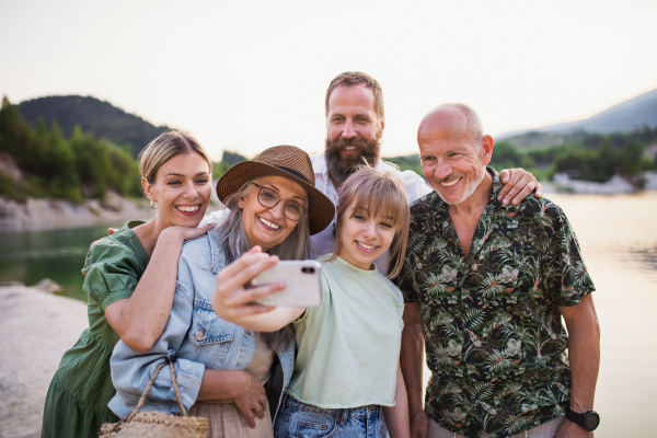 A happy multigeneration family on hiking trip on summer holiday, taking selfie.