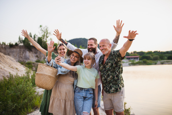 A happy multigeneration family on hiking trip on summer holiday, taking selfie.