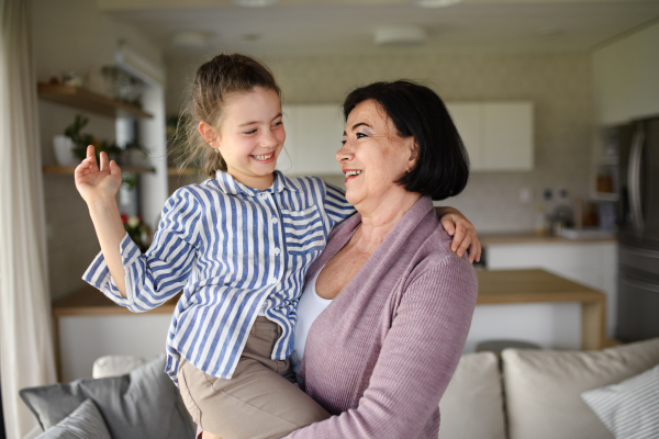 A happy small girl with senior grandmother indoors at home having fun.