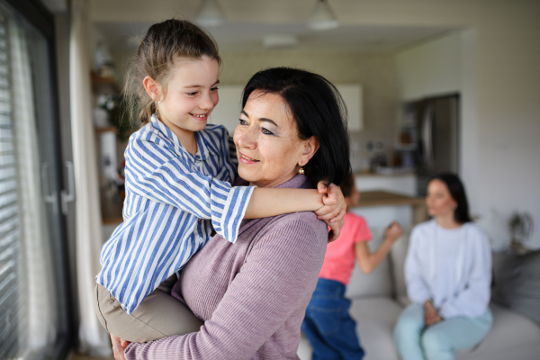 A happy small girl with senior grandmother indoors at home having fun.