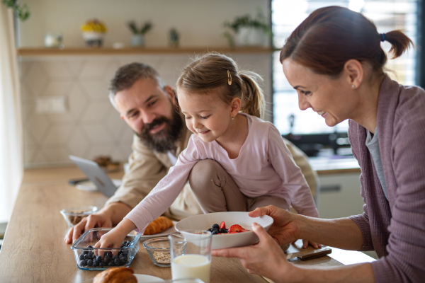 A family with small daughter indoors in kitchen, everyday life and home office with child concept.