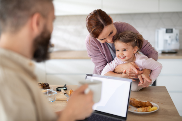 A family with small daughter indoors at home, everyday life and home office with child concept.