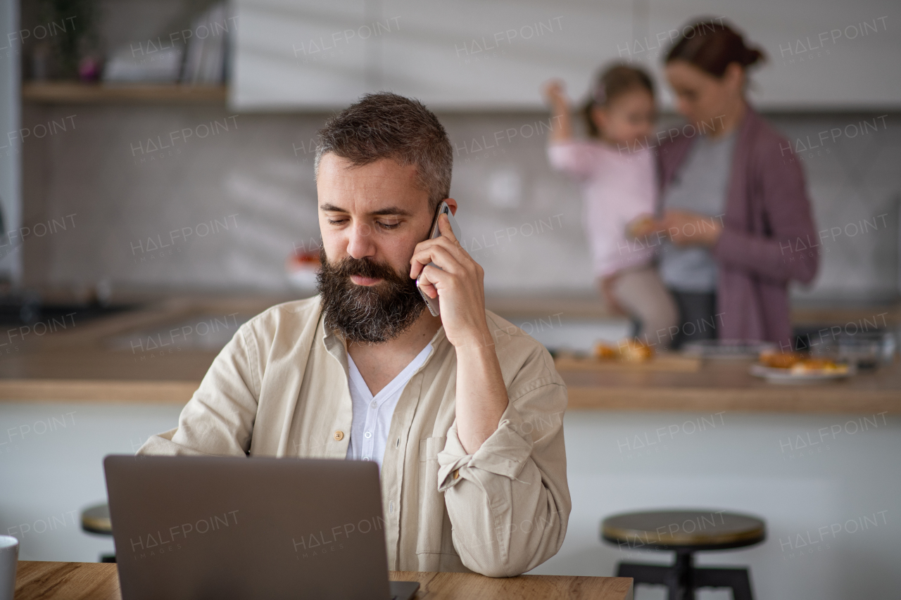 Mature businessman having video call indoors at home, everyday life and home office with child concept.