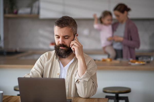 Mature businessman having video call indoors at home, everyday life and home office with child concept.