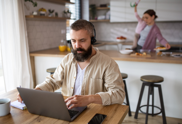 Mature businessman having video call indoors at home, everyday life and home office with child concept.