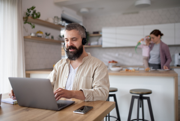 Mature businessman having video call indoors at home, everyday life and home office with child concept.